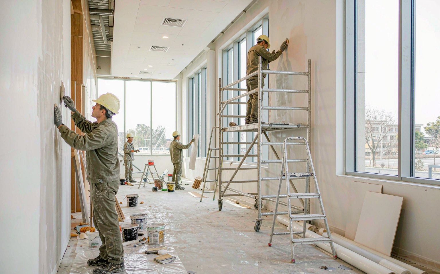 Trabajadores aplicando acabados interiores en un edificio en obra gris